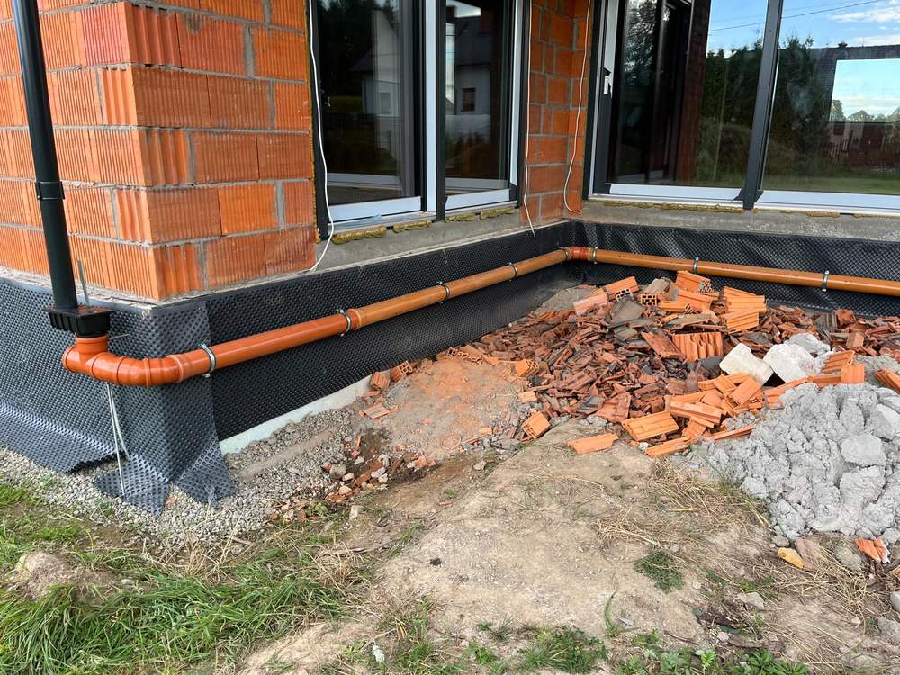 Odwodnienie i rury kanalizacji deszczowej przy fundamencie budynku